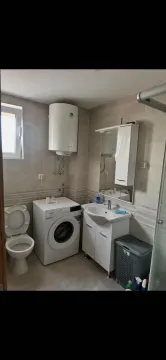 Compactly equipped bathroom with a washbasin, washing machine, and toilet. - image 4
