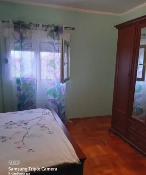 Spavaća soba sa bračnim krevetom, drvenim ormarom i prozorom sa zavjesama. - image 5