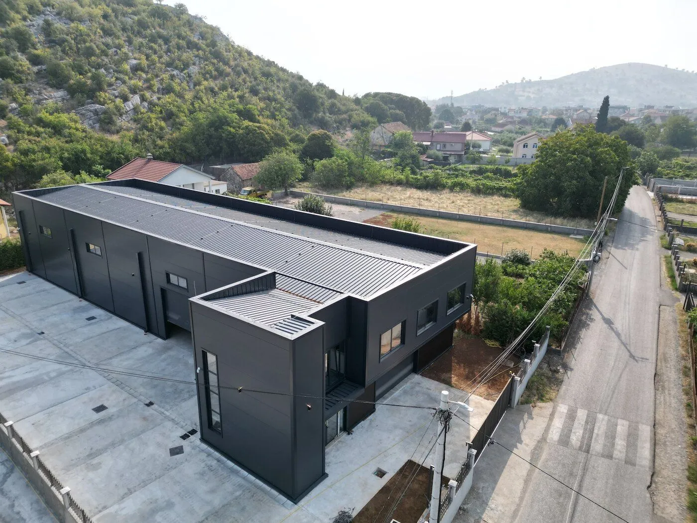 Aerial view of a modern commercial building with a dark facade and surrounding property.