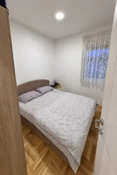 Small bedroom with a double bed, parquet flooring, and a curtained window. - image 6