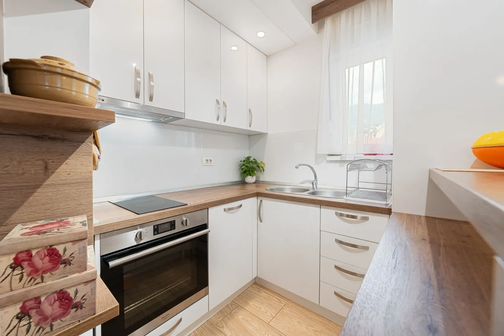 Small kitchen with white cabinets, wooden countertops, and a built-in oven.