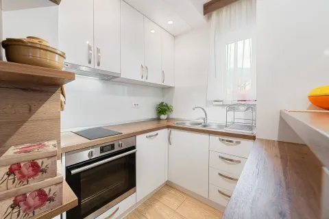 Small kitchen with white cabinets, wooden countertops, and a built-in oven. - image 10