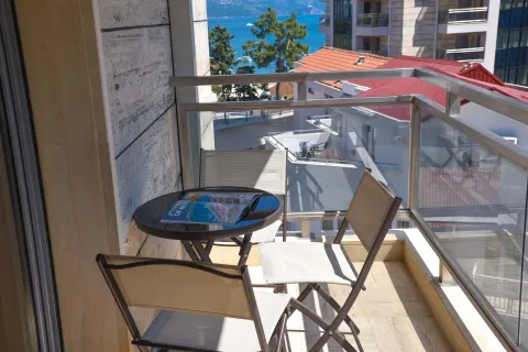 Small furnished balcony with a table, chairs, and a sea view. - image 3