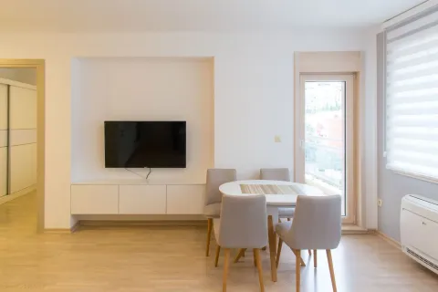 Living room with a dining table and chairs, wall-mounted TV, and access to the terrace. - image 9