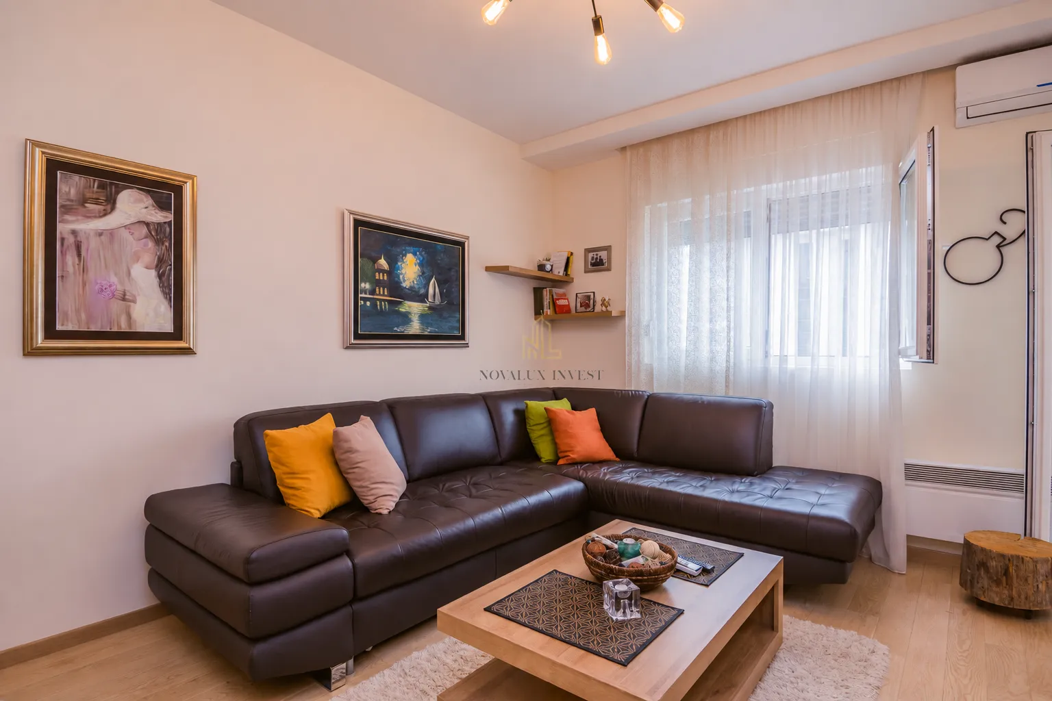 Living room with a sectional sofa, coffee table, and paintings on the wall.