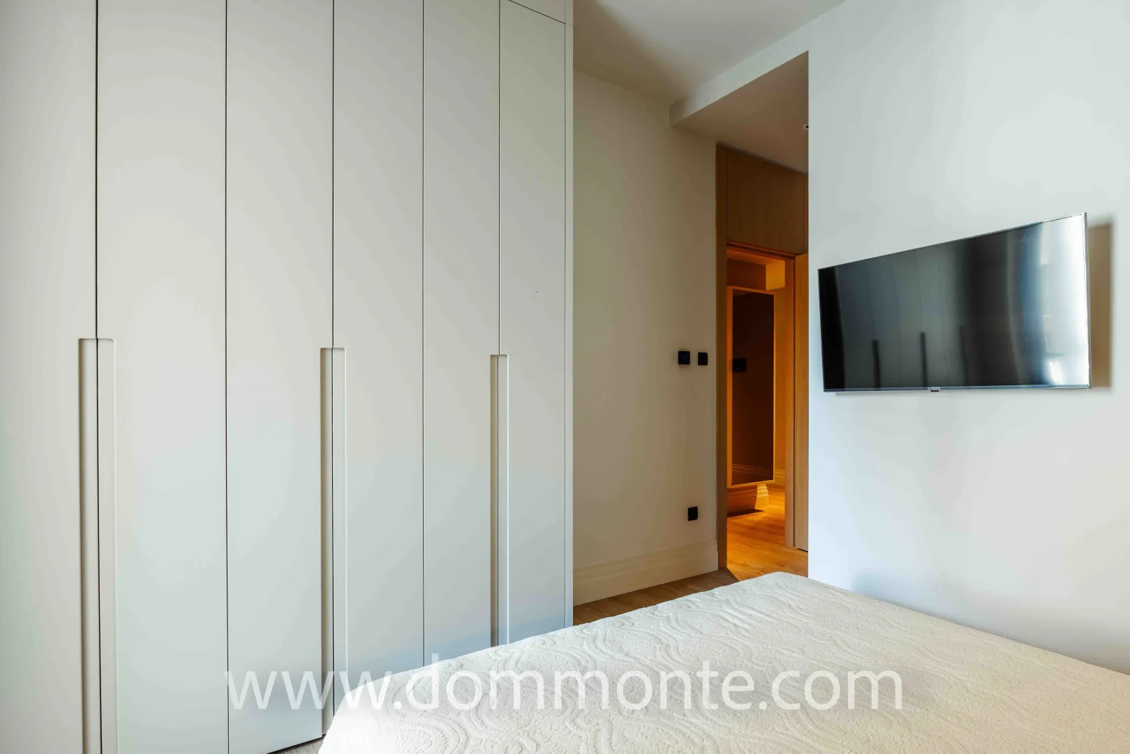 Modern bedroom with built-in wardrobe, bed, and wall-mounted television.