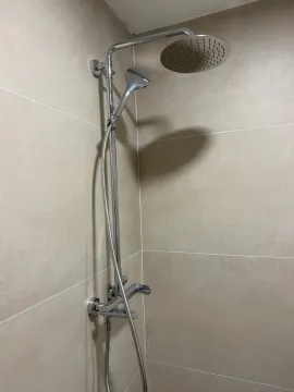 Close-up of a modern shower system in a sand-tiled bathroom. - image 8