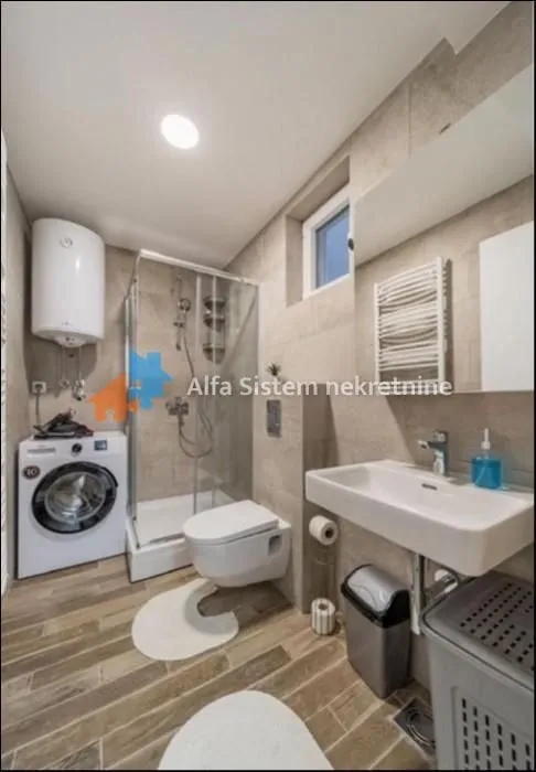 A modern bathroom equipped with a shower cabin and a washing machine.