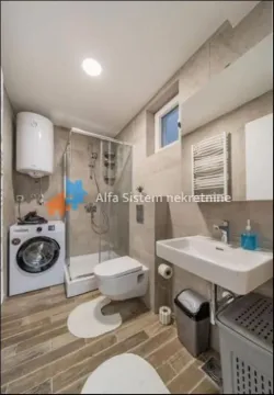 A modern bathroom equipped with a shower cabin and a washing machine. - image 10