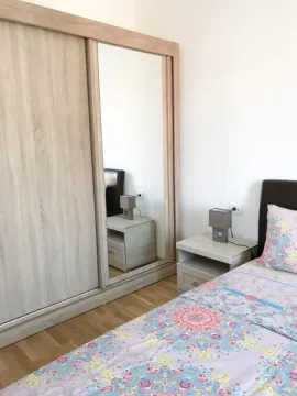Spavaća soba sa velikim garderoberom sa ogledalom, krevetom i noćnim stočićem. - image 2