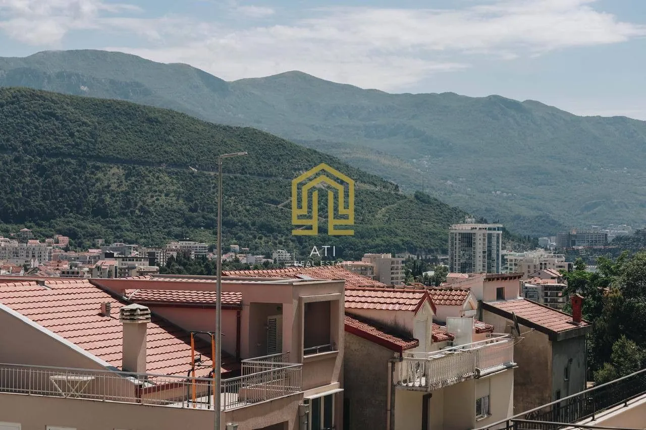Pogled sa terase na grad i planine u pozadini.