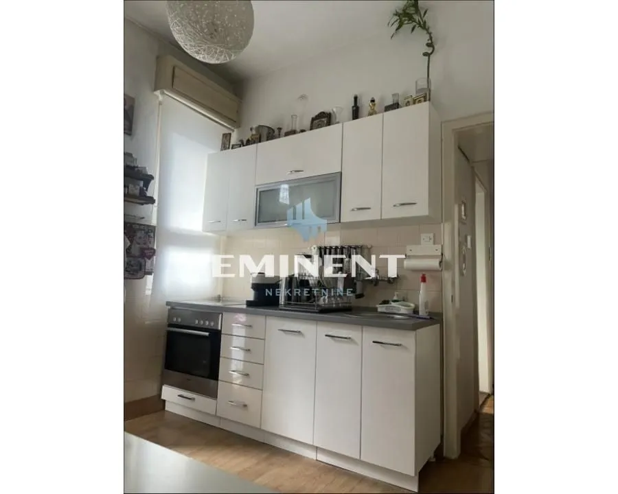 Small white kitchen with upper and lower cabinets and a built-in oven.
