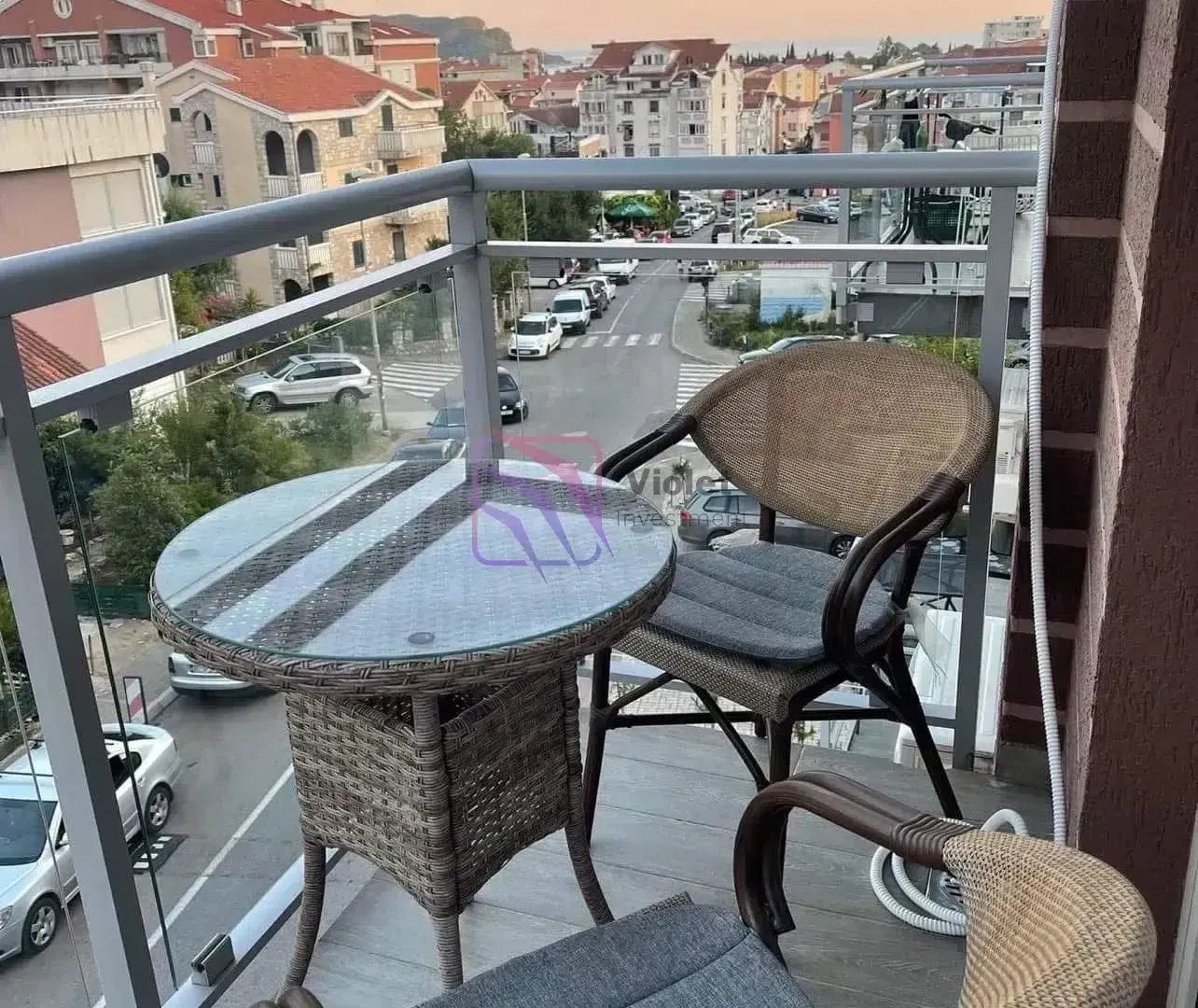 Namješten balkon sa stolom i stolicama i pogledom na ulicu.