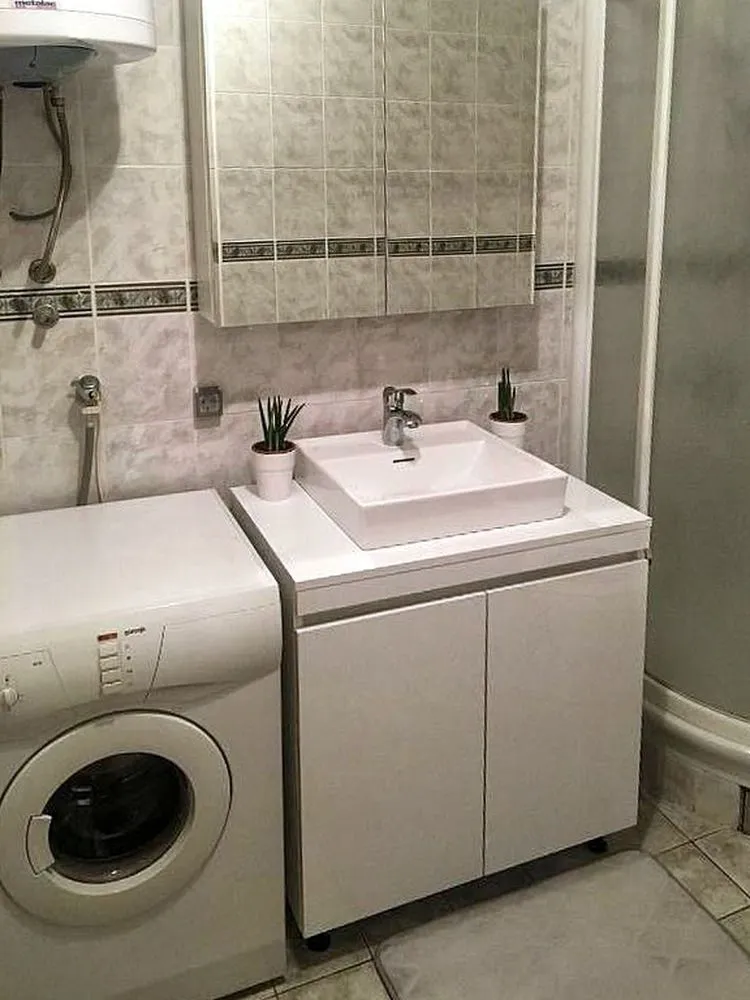 Kupatilo sa umivaonikom, ormarićem, veš mašinom i tuš kabinom.