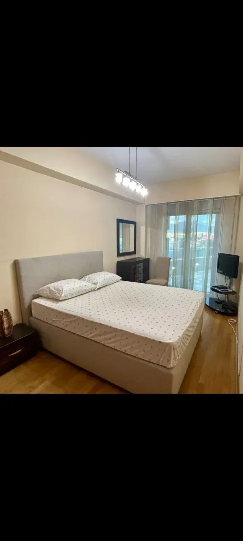 Bright bedroom with a double bed, a dresser, and access to the balcony.