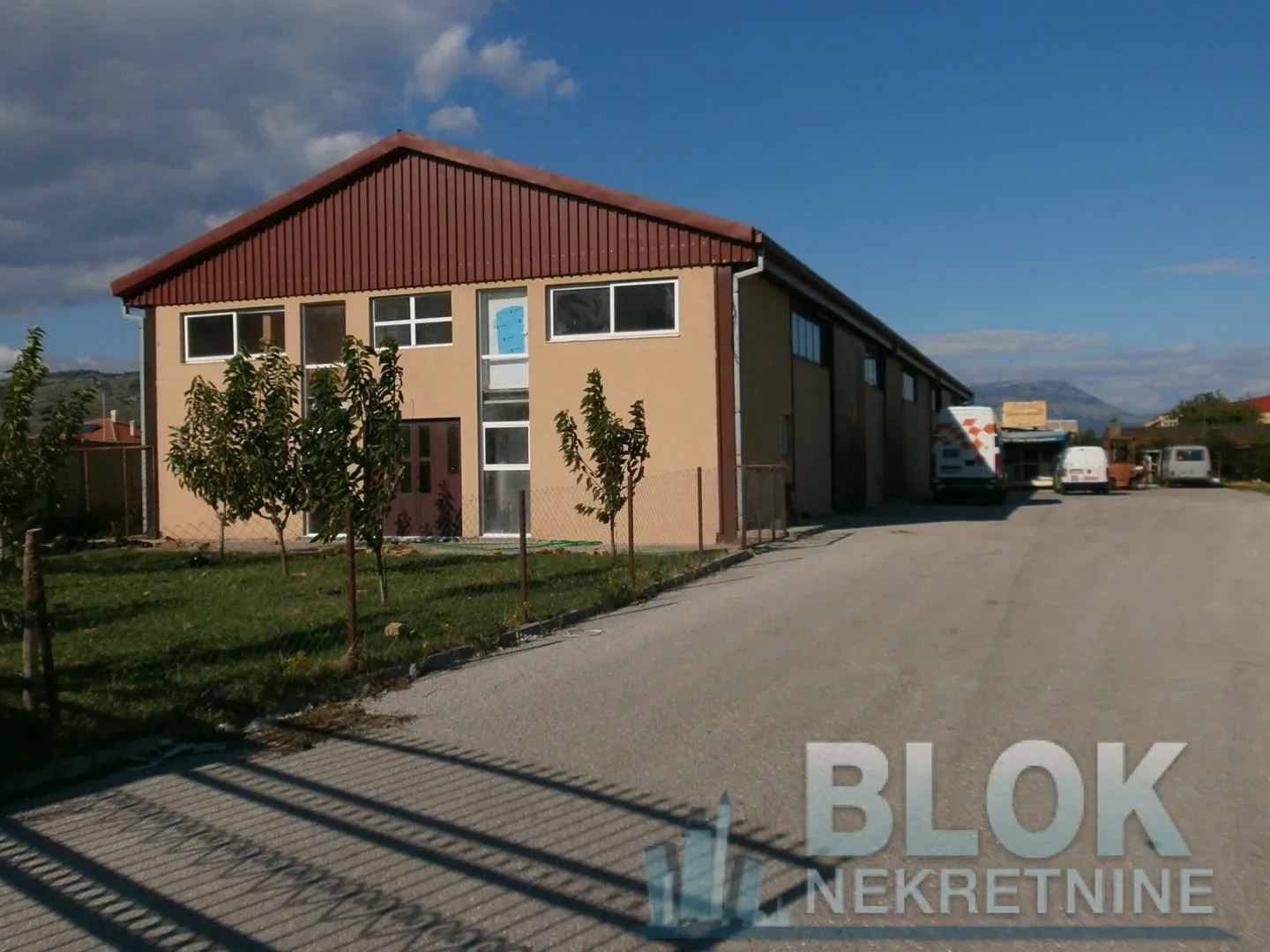 Exterior view of the commercial building with a warehouse and access road.