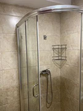 Kupatilo sa staklenom tuš kabinom i bež pločicama. - image 3