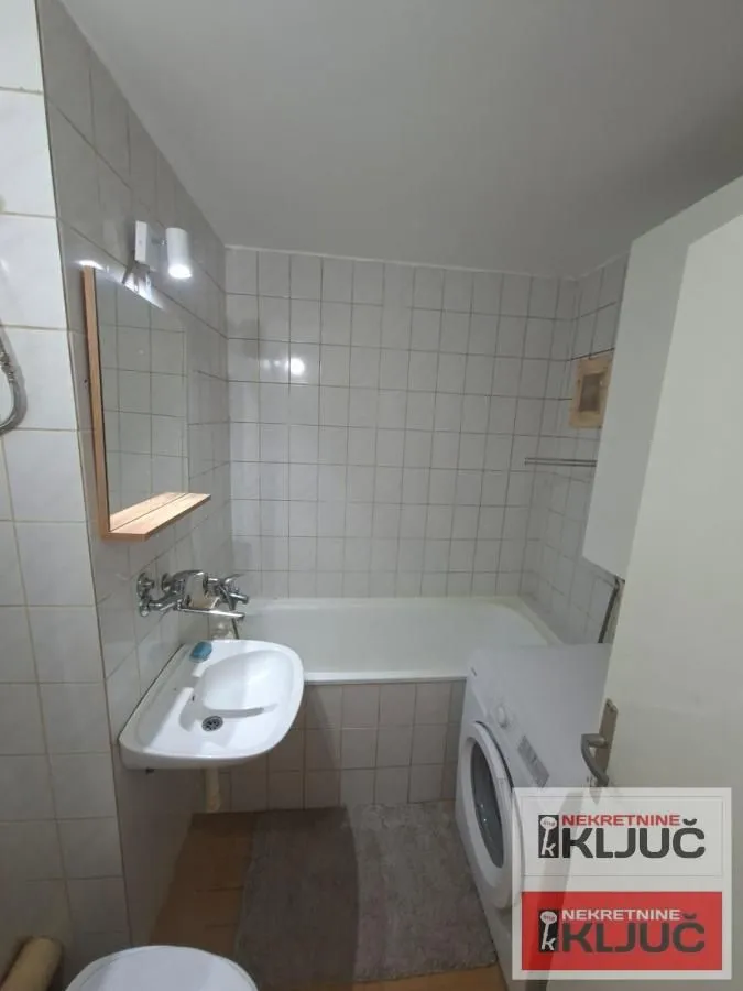 Manje kupatilo sa kadom, umivaonikom i veš mašinom.