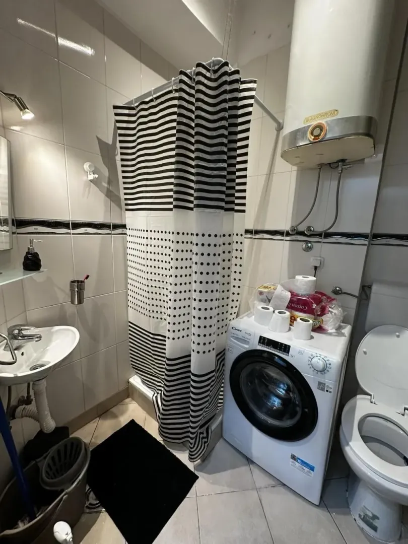 Manje kupatilo sa tuš kabinom, umivaonikom, WC šoljom i veš mašinom.
