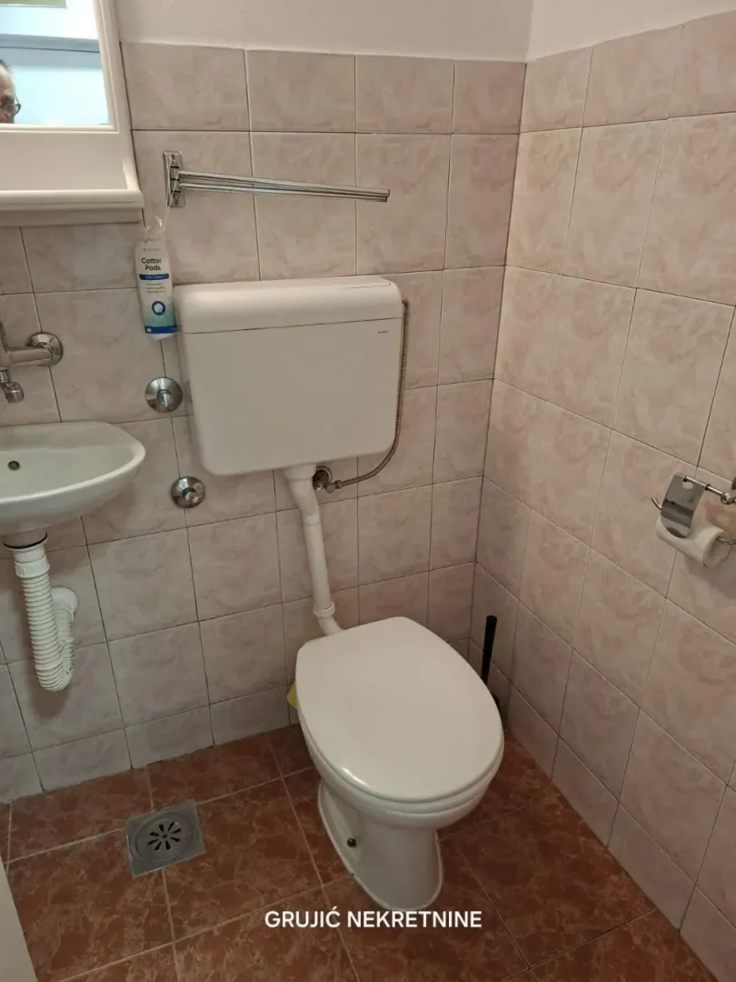 Manje kupatilo obloženo keramičkim pločicama sa WC šoljom i umivaonikom.