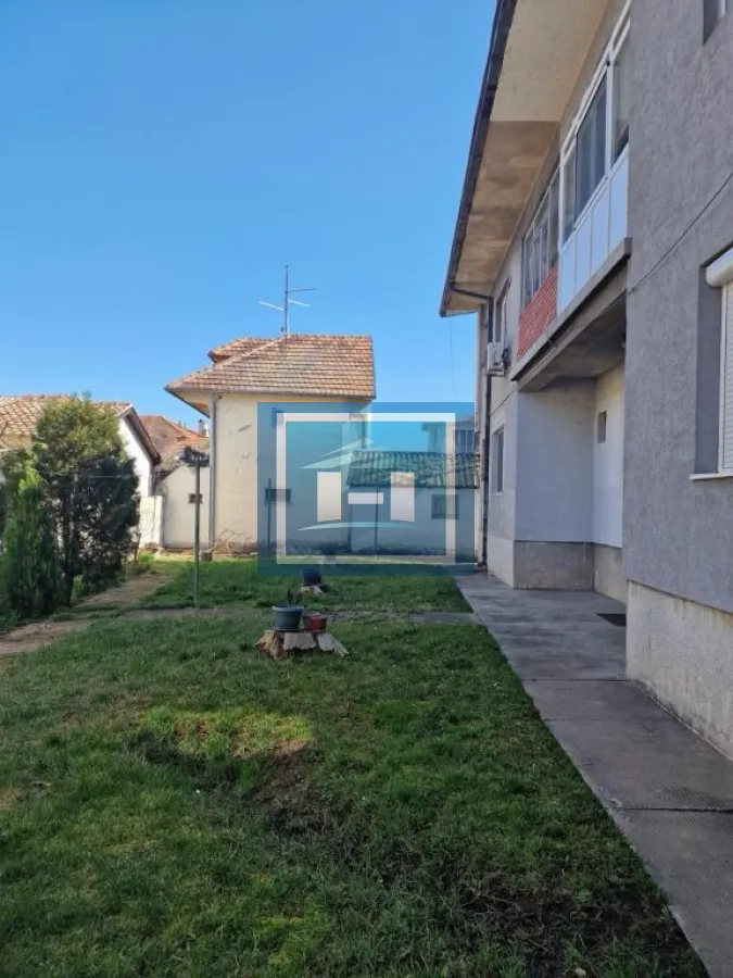 Dvorište sa travnjakom i pogledom na fasadu zgrade.