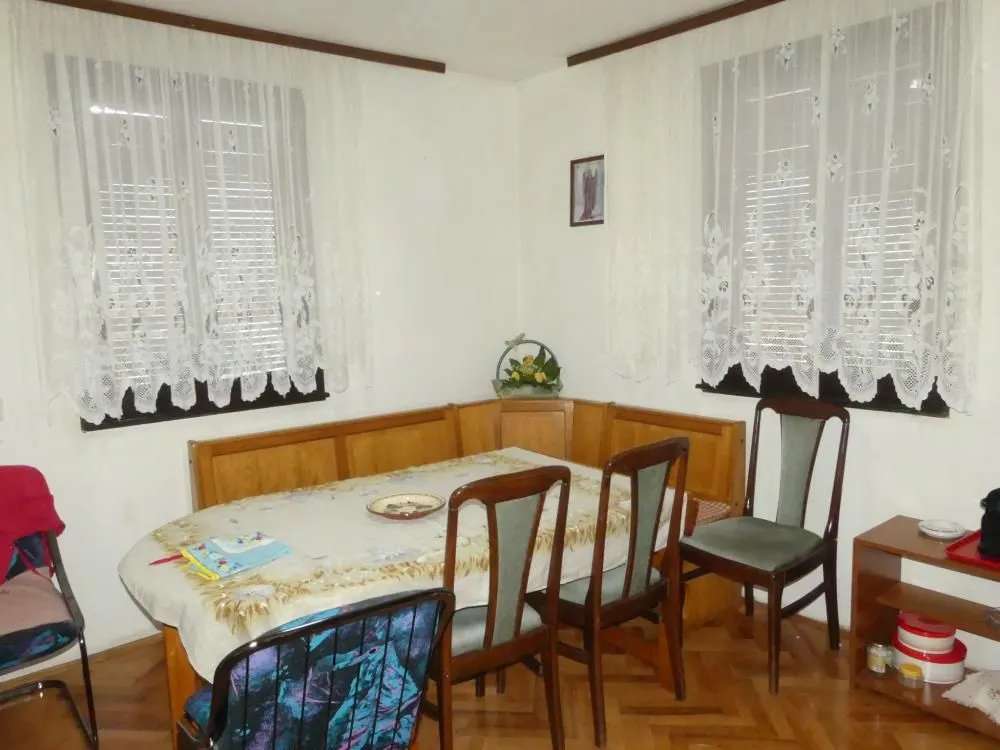 Dining area with a wooden table, corner bench, and chairs by the windows.