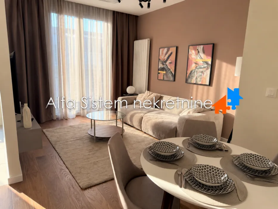 Living room with a sofa, coffee table and a dining area in the foreground.