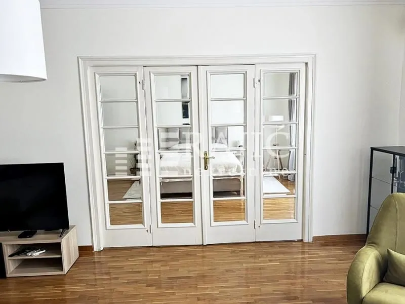Living room with white double glass doors and a view into the bedroom.