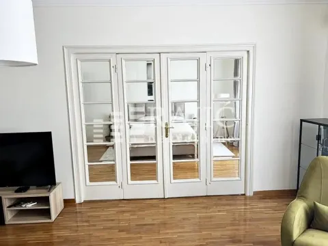 Living room with white double glass doors and a view into the bedroom. - image 3