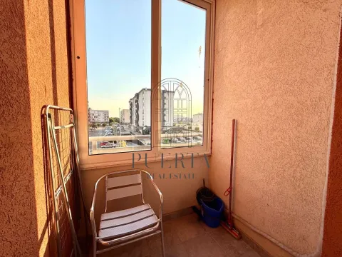 Smaller covered balcony with a chair, drying rack, and city view. - image 6