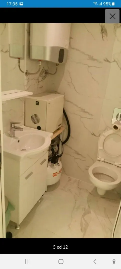 Small bathroom with a sink, boiler, and toilet.