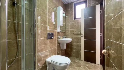 Kupatilo obloženo keramičkim pločicama sa tuš kabinom, umivaonikom i wc šoljom. - image 25