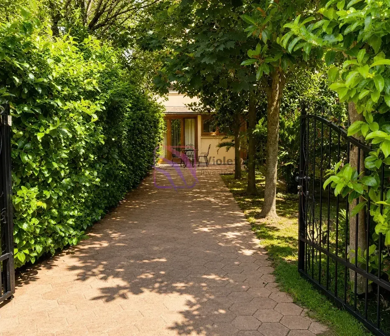 Paved path with a gate and greenery leading to the house entrance.