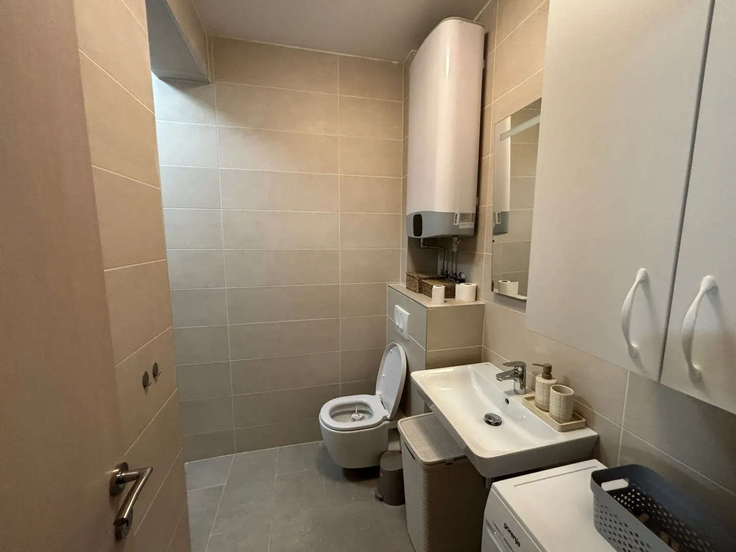Small tiled bathroom equipped with a washbasin and toilet.
