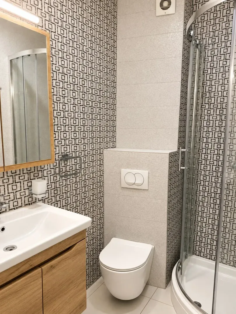 Modernly equipped bathroom with a shower cabin, washbasin, and toilet.