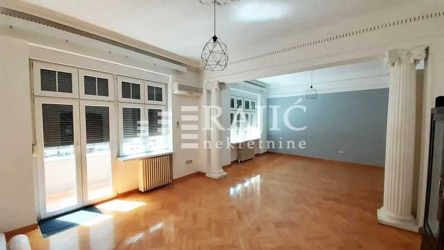 Spacious bright living room with parquet flooring and decorative columns.