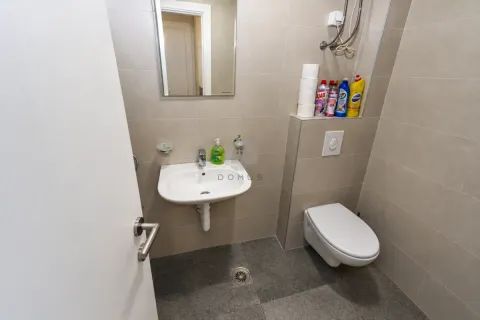 Compact bathroom with a sink, mirror, and toilet tiled with ceramic tiles. - image 14