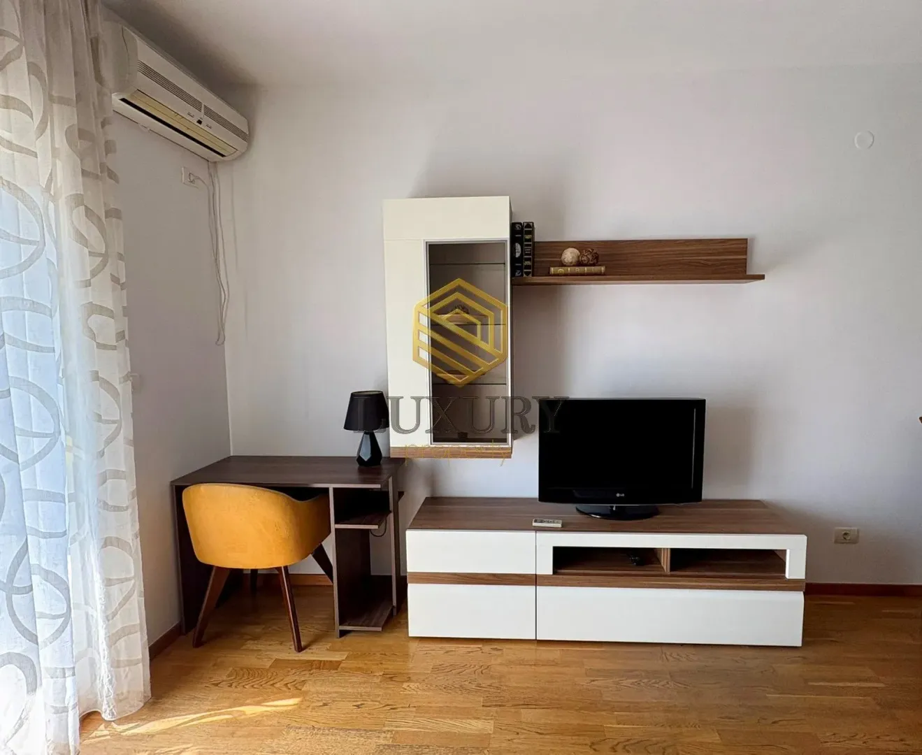Living room with a TV unit, desk, and shelves.