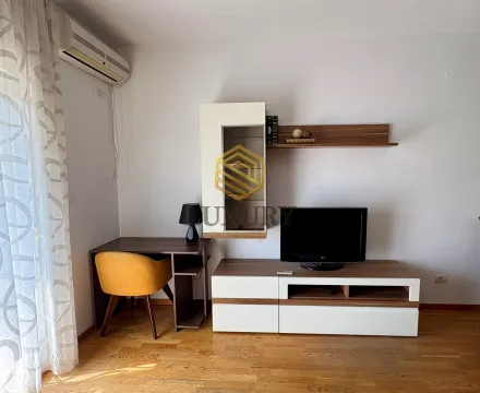 Living room with a TV unit, desk, and shelves. - image 6