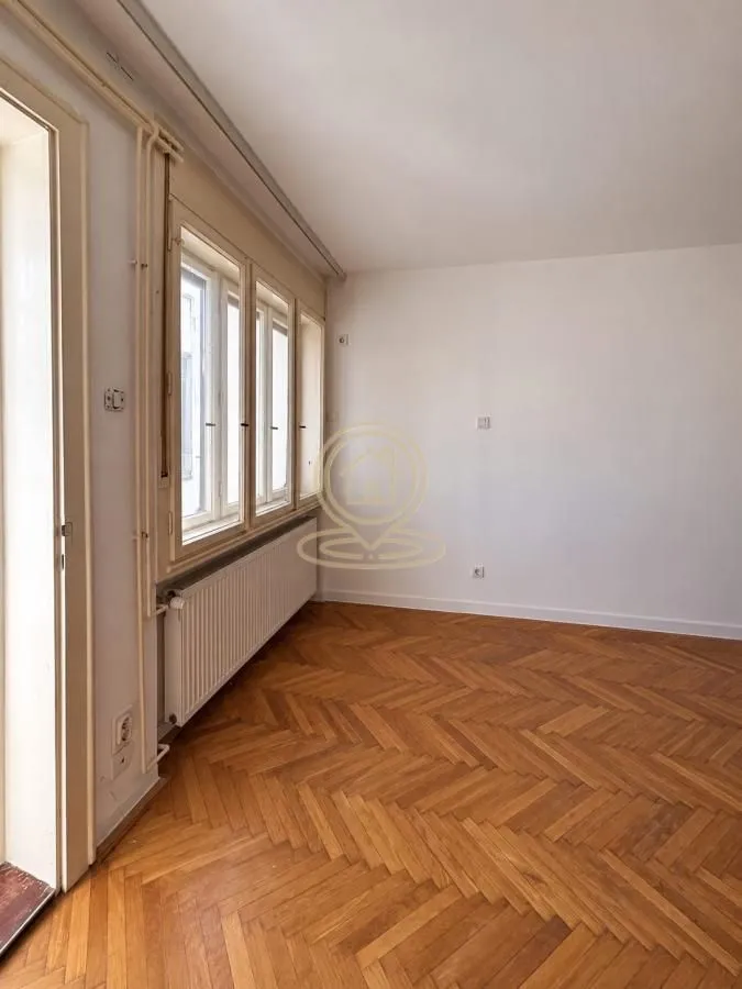 Empty room with parquet flooring and windows.