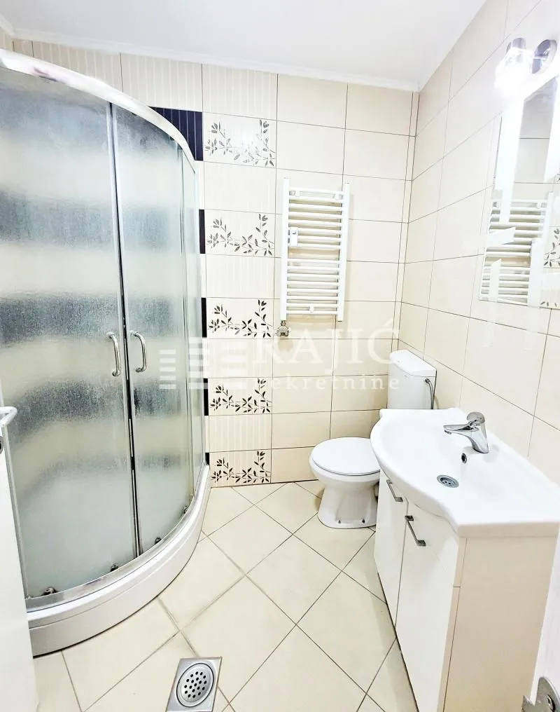 Furnished bathroom with a shower cabin, sink, and toilet.