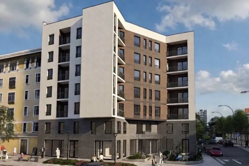 Exterior view of a modern apartment building with balconies and surrounding area.