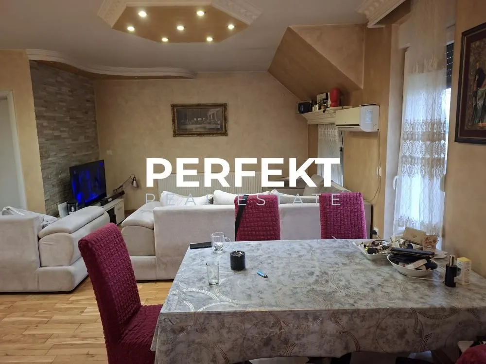 Dnevna soba sa garniturom za sedenje i trpezarijskim stolom.