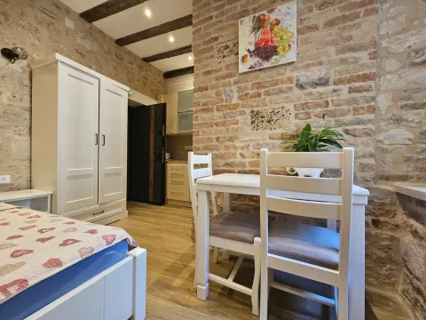 Namještena spavaća soba sa zidom od kamena i bijelim namještajem. - image 4