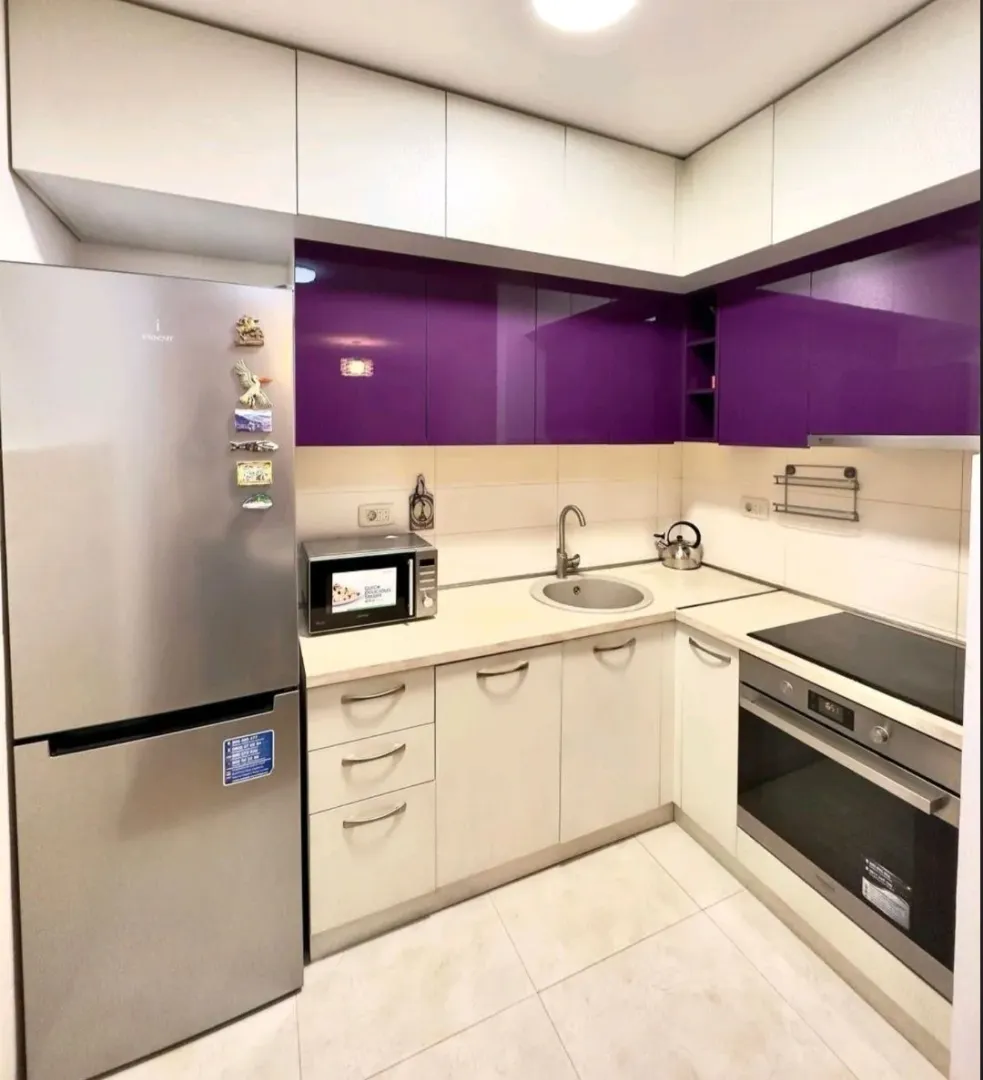 Small kitchen with white and purple cabinets and built-in appliances.