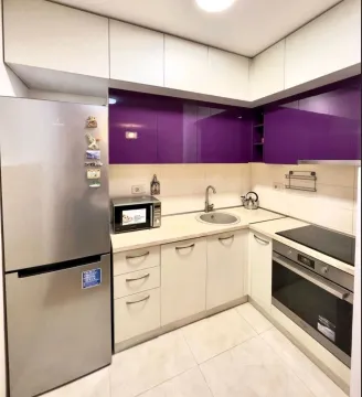 Small kitchen with white and purple cabinets and built-in appliances. - image 2