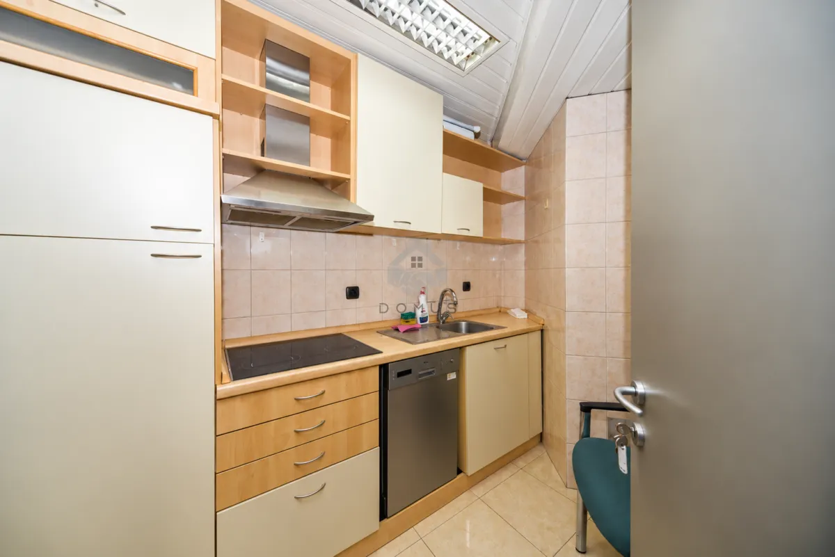 Compact kitchen with wooden cabinets, sink, built-in cooktop, and dishwasher.