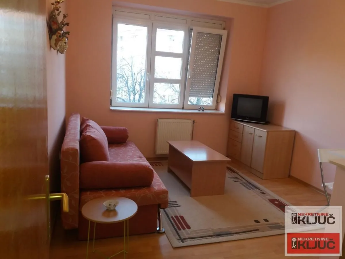 Living room with a sofa, coffee table, and television.