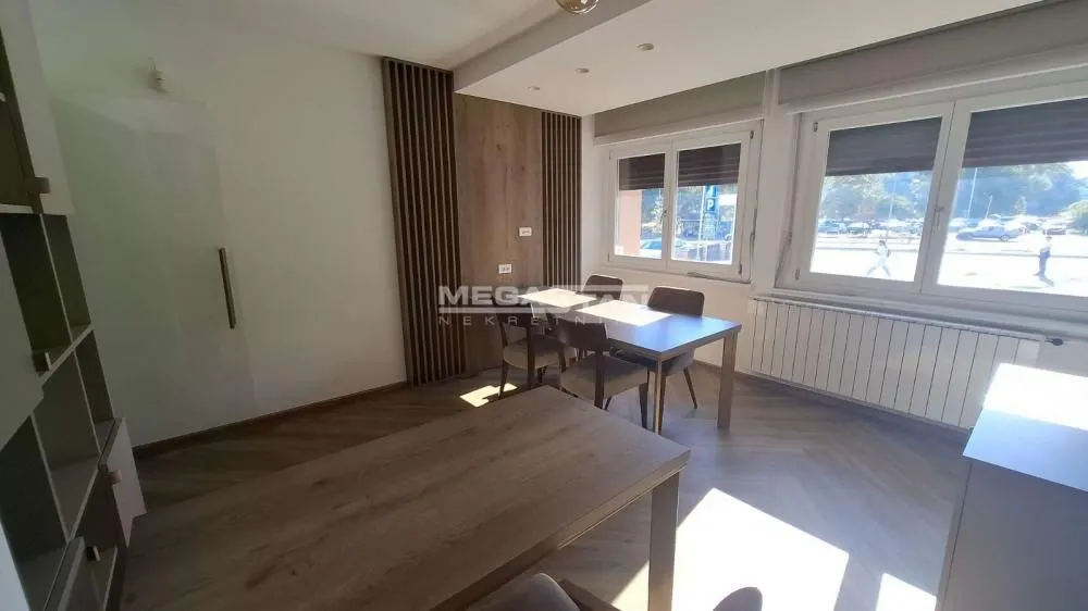 Living room with a dining area, wooden furniture, and two windows.