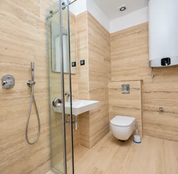 A modern bathroom equipped with a walk-in shower, washbasin, toilet, and water heater. - image 4